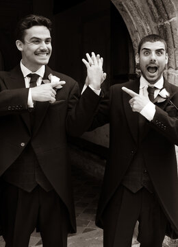 Gay couple laughing and smiling and they leave church after getting married, pointing at each other's rings