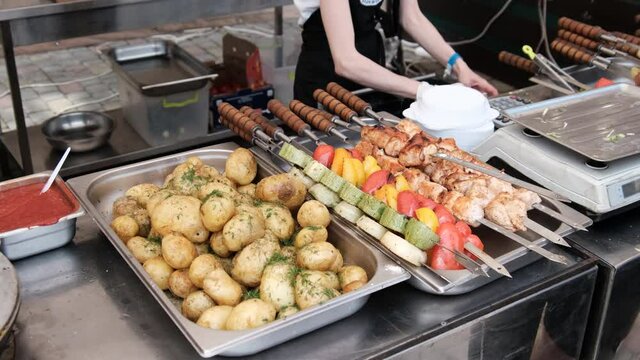 Ready-to-eat street food, shashlik, meat, potatoes, grilled vegetables are on display food court. Food court with variety of grilled ready meals at the festival. Various baked food on BBQ in showcase