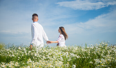 Couple walking in poppy field holding hands smiling, love and romance