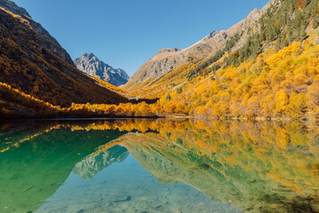Mountain lake with crystal water, reflection and autumnal trees.
