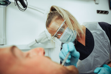 Caucasian male client sitting in dentist chair while nurse evaluates dirty teeth