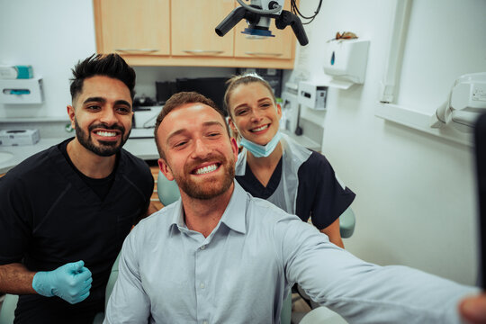 Caucasian Male Taking Selfie With Male And Female Nurse Wearing Surgical Masks In Doctors Office