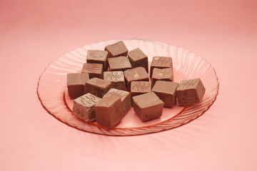 dark chocolate on a plate on pink background 