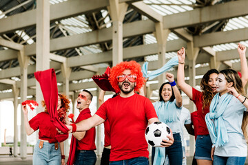 Sport football fans in red and blue t-shirt supporting their team while going to the stadium -...