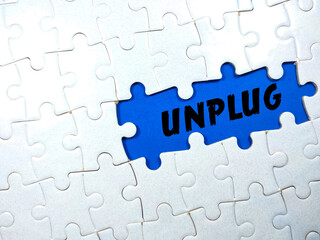 Selective focus.Text UNPLUG with jigsaw puzzle on blue background.