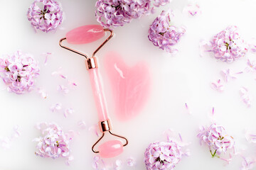 Roller facial massager and lilac in milk . Facial care. Skin care. Cosmetology. Massage. Lilac bush.