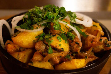 a frying pan with potato meat and fried onions on a wooden table. the concept of Caucasian and Russian cuisine