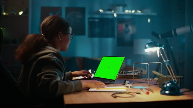 Young Teenage Multiethnic Girl Making a Video Call on Laptop Computer with a Green Screen Chromakey Mock Up Display. Talking with Friends and Colleagues, Attending Online Class. Doing School Homework.