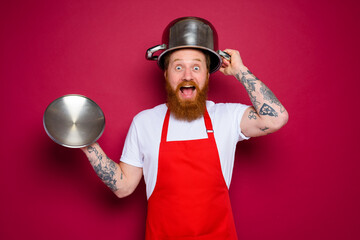 amazed chef with beard and red apron plays with pot