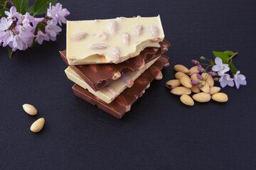 bars of milk and white chocolate with almond nuts and a bunch of almonds, a sprig with flowers