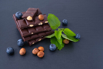 chocolate bars with hazelnuts, next to mint, blueberries and hazelnuts