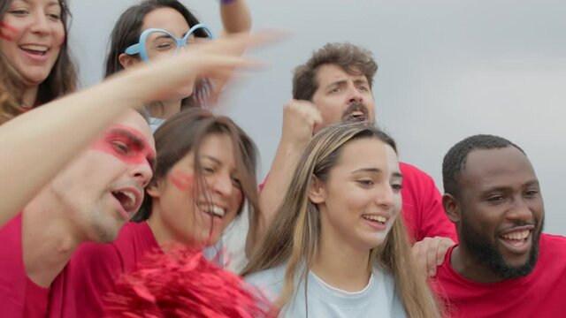 Multiracial group of spectators friends in team colours watching sports event at stadium - Championship and sport entertainment lifestyle concept