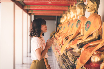 Asian woman is worshiping Buddha statue in Pho temple in Bangkok, Thailand.