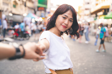 Young woman is holding his couple 's hand on Khao San Road in Bangkok, Thailand.