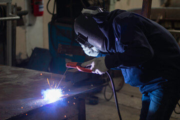 Skillful welders weld steel in the factory. Construction site metal welder.