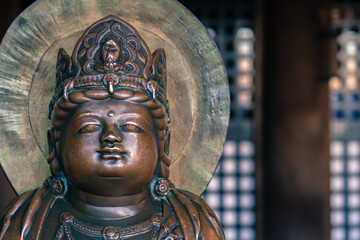 Obraz premium Small bronze Buddha statue with crown on his head in an old Buddhist temple of Kiyomizu Dera in Kyoto, Japan. Arts and symbols of Buddhism in the far east.