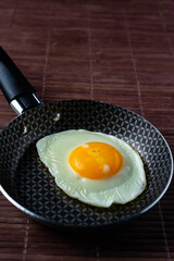 Frying pan with fried egg on a bamboo table
