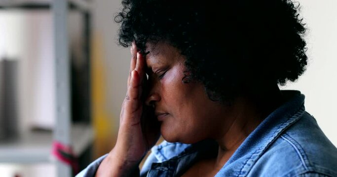 Worried black woman feeling anxiety rubbing face with hand