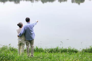 Happy old couple watching the scenery by the lake