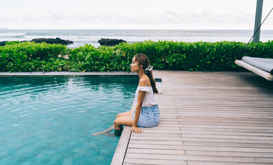 Calm ethnic woman relaxing at poolside