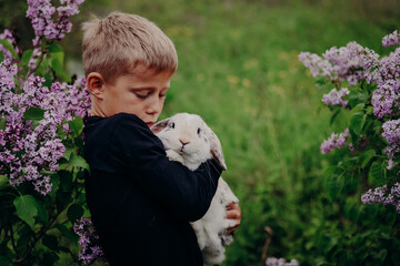 A blond boy hugging his pet. A lop-eared tricolour rabbit.