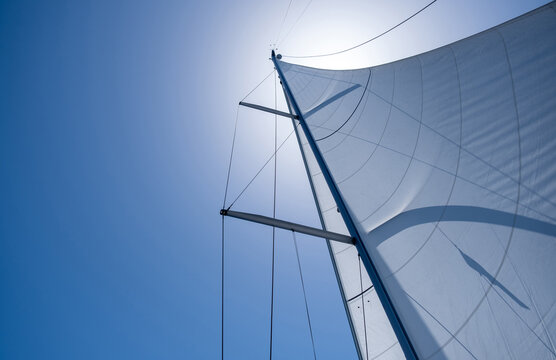 Yacht sails on clear blue sky background. Sailing with the wind at open sea ocean, summer holidays