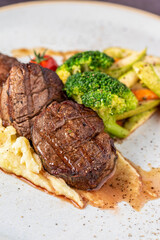 Grilled beef tenderloin steak on a ceramic plate with butter and thyme. Filet Mignon recipe with vegetables