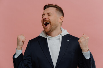 Happy excited man with closed eyes raising clenched fists and celebrating victory