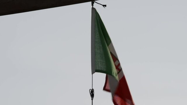 the Italian flag blowing in the wind with the sea in the background