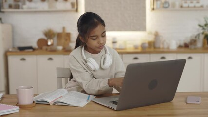 Indian girl using modern laptop while doing homework