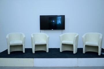 An interactive empty room: white chairs placed on podium and monitor