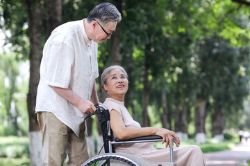 Obraz premium The old man pushes his wife in a wheelchair