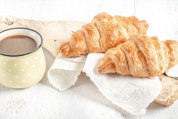 crispy croissants and cup of coffee on a wooden table