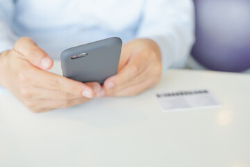 Smartphone Mobile phone hold touch in a Asian people hand in coffee shop restaurant waiting for friends with hand touching a Smart Phone, Technology smartphone communication Background Concept