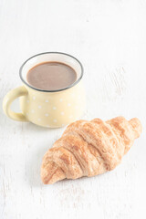 crispy croissants and cup of coffee on a wooden table