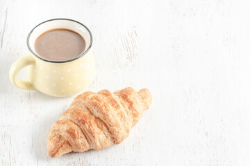 crispy croissants and cup of coffee on a wooden table