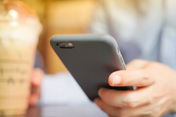 Smartphone Mobile phone hold touch in a Asian people hand in coffee shop restaurant waiting for friends with hand touching a Smart Phone, Technology smartphone communication Background Concept