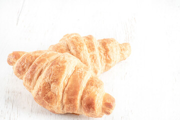 two crispy croissants on a wooden table