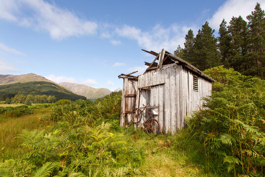 Abandoned shed in the Scottish Highlands with a broken rusted bike outside  - UK