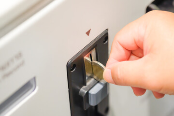 A asian man's hand inserting coin in to a vending machine slot machines ATM, Automatic Machine Technology for deposit or withdraw money business financial Background Concept