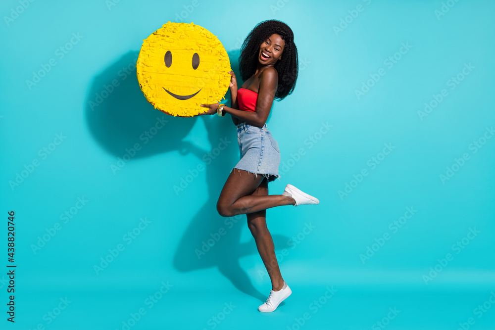 Wall mural Full length photo of dark skin happy cheerful young woman hold hands big emoji smile isolated on blue color background