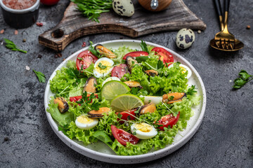 Fresh salad with mussels, quail, egg, conjugate, lime, spinach, lettuce, cherry tomatoes and microgreen. Dietary salad. Food recipe background. Close up