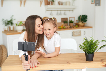 Mom and daughter are having fun and fooling around while recording a video blog. Lifestyle....