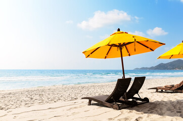 Beach chairs with yellow umbrella and beautiful sand beach in Koh Samui, Thailand.