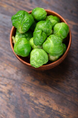 Bunch of fresh Bruxelles sprouts in a cup on wooden background.