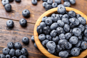 Freshly picked blueberries in wooden bowl on a wooden  table.