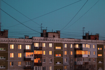 windows reflecting the sunset sky, soviet building, wires on the sky background