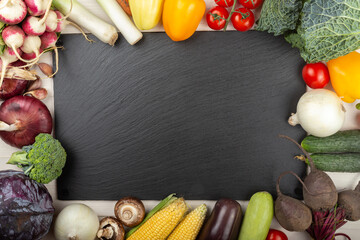 Organic food frame. Fresh raw vegetables from the home garden. On a black board. Healthy food, diet concept. Space for text.