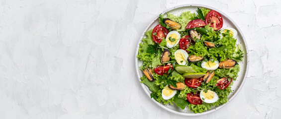 Healthy green salad preparation with salad leaves, mussels, quail, egg, conjugate, lime, spinach, lettuce, cherry tomatoes and microgreen. Dietary salad. Long banner format. top view