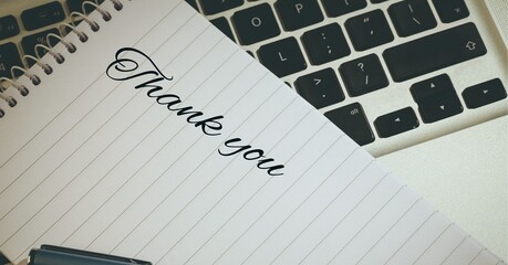 Composition of thank you note with pen over computer keyboard
